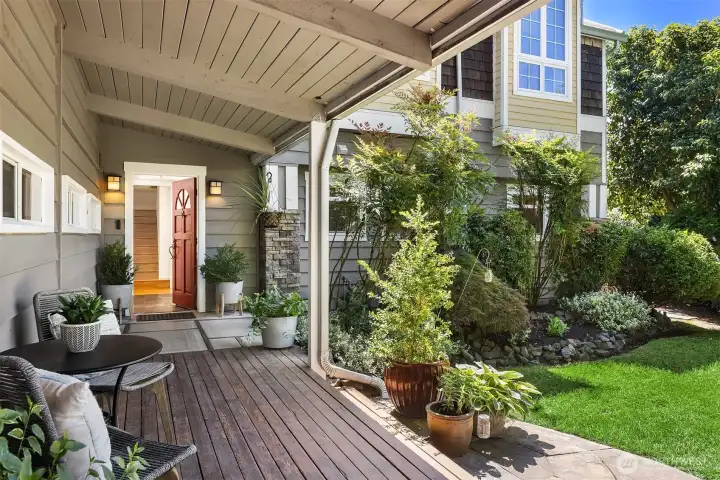A welcoming redwood-covered porch creates a warm introduction, blending indoor comfort with the lush, garden-like setting beyond.