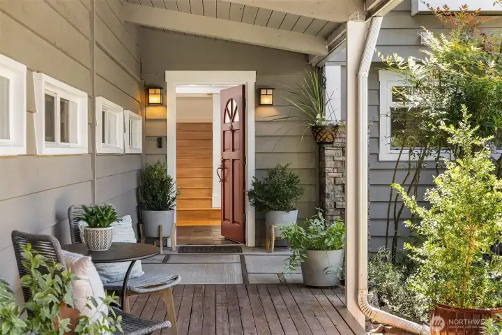 The inviting covered entry welcomes guests with warm redwood decking, garden views, and a charming sense of arrival that immediately feels like home.