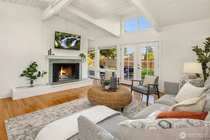 An oversized masonry wood-burning fireplace anchors the vaulted living room, adding warmth, character, and a timeless sense of comfort to the light-filled gathering spaces.