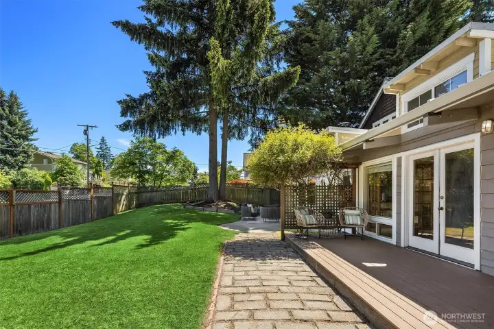 Designed for effortless outdoor living, the expansive patio and level backyard create a private retreat for entertaining, play, gardening, or peaceful afternoons beneath the towering evergreens.