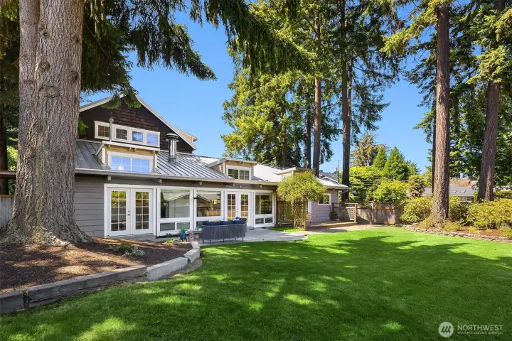Towering evergreens and an expansive level lawn create a rare backyard setting that feels both private and park-like — an inviting extension of the home designed for gathering, play, and everyday outdoor living.
