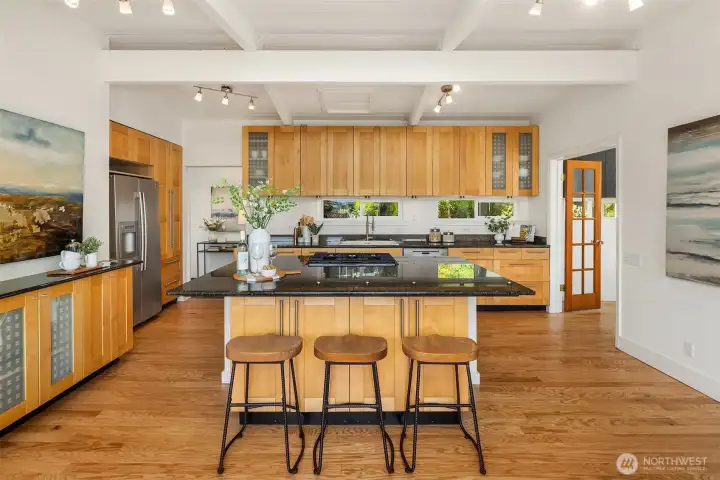 A generous island anchors the open-concept kitchen, where vaulted ceilings, warm wood cabinetry, and expansive prep space create a functional yet inviting gathering place at the heart of the home.