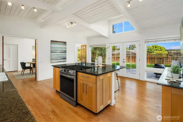 Vaulted ceilings and expansive windows fill the kitchen with natural light, while French doors create seamless access to the private patio and backyard beyond — blending everyday living with effortless indoor-outdoor connection.