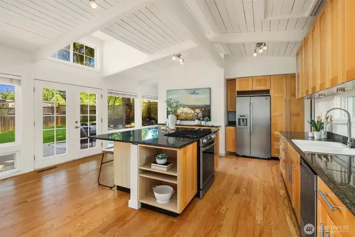 The light-filled kitchen pairs vaulted ceilings and warm wood finishes with expansive prep space and seamless indoor-outdoor flow, creating an inviting hub designed for both entertaining and everyday living.
