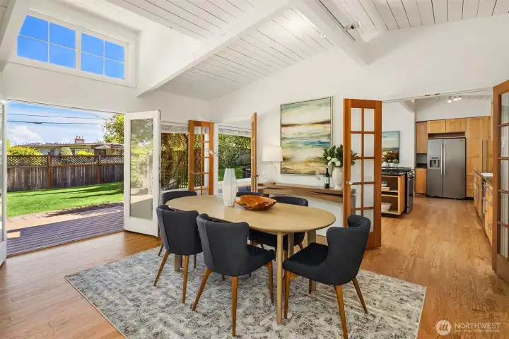 Vaulted ceilings and expansive windows bathe the dining area in natural light, while French doors open to the private patio and backyard — creating a warm, inviting setting for both intimate dinners and larger gatherings.