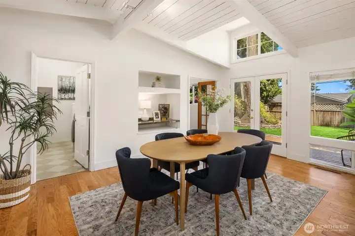 Vaulted ceilings and expansive windows bathe the dining area in natural light, while French doors open to the private patio and backyard — creating a warm, inviting setting for both intimate dinners and larger gatherings.