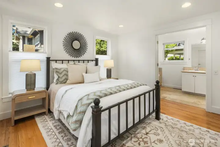 The main-floor primary suite offers a peaceful retreat with warm hardwood floors, generous natural light, and a spacious ensuite bath designed for comfort and ease.
