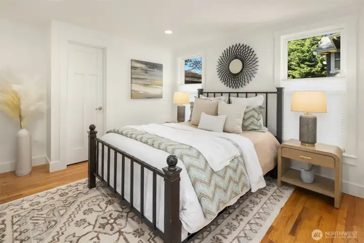 The main-floor primary suite offers a peaceful retreat with warm hardwood floors, generous natural light, and a spacious ensuite bath designed for comfort and ease.
