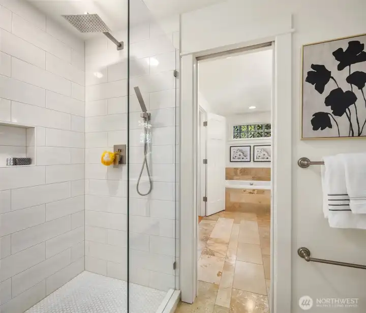 The main-floor bath pairs clean white millwork with warm stone finishes and includes a shower for comfortable everyday living and guest convenience.