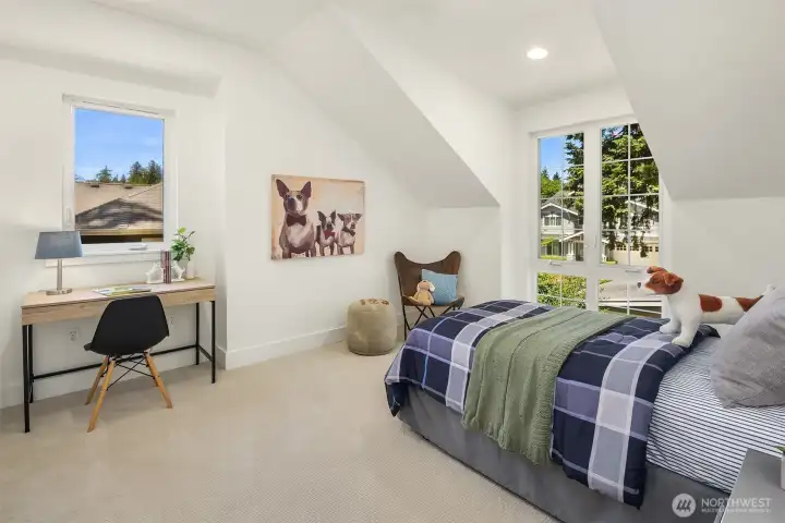 Bright and inviting, this upper-level bedroom features soaring angular ceilings, oversized windows, and a flexible layout with room for study, play, or quiet retreat.