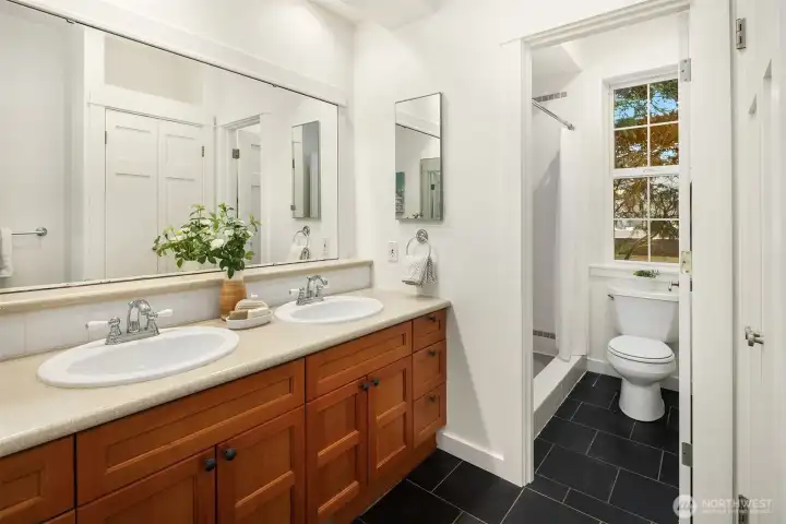 Well-appointed upper-level bath with dual-sink vanity, generous storage, and a separate shower room designed for everyday ease and functionality.