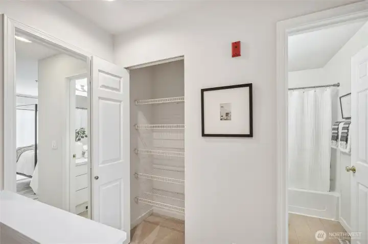 Linen closet just outside the primary suite with access to the hall bathroom just beyond.