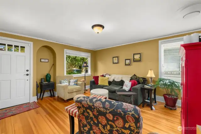 The living room has large windows and hardwood floors.