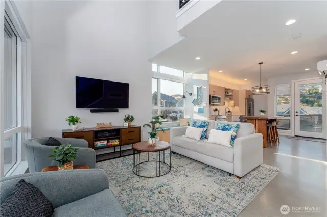 View 1 of the Great Room/Living Room w/ vaulted ceilings, oversized windows and doors leading to the outdoor living area.