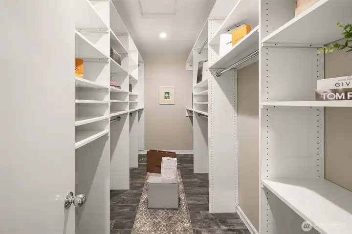 Huge walk in closet in primary suite with custom shelving.
