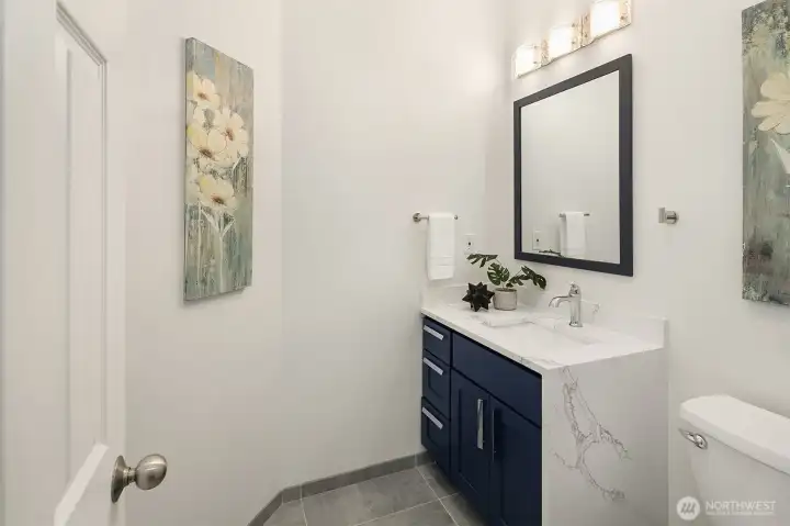 Powder room off of mud room has waterfall quartz countertops.