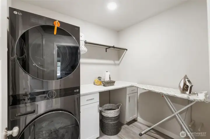 Utility room with tower LG washer/dryer (stays with the house). Quartz counter for folding and hanging rod.