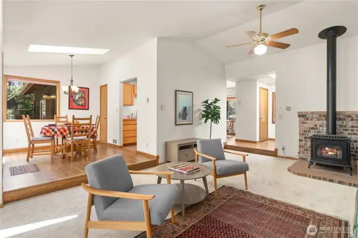 Living room features a ceiling fan and gas-logs free-standing fireplace. skylight over the dining table.
