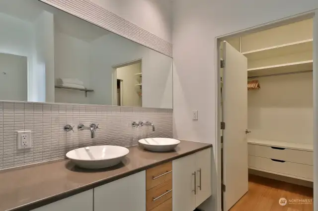 Primary bath and opening to walk in closet that houses the washer, dryer, and also serves as a utility room.