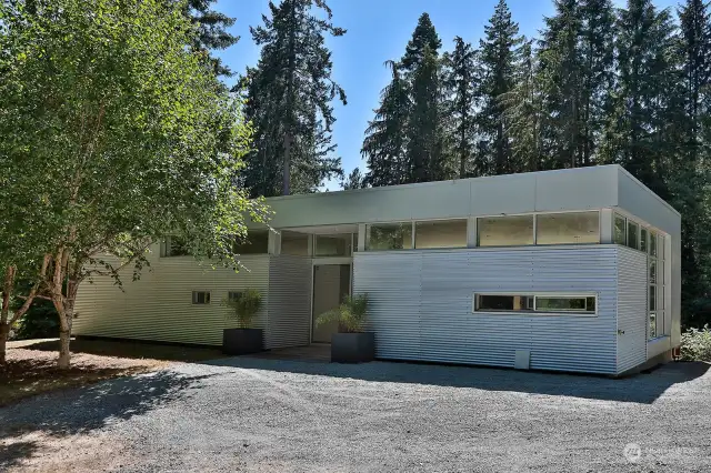 Eastside of home with entrance between bamboo planters. Kitchen windows to the right of entrance, small windows to the left are main 3/4 bath. Upper windows allow natural light to fill your home.