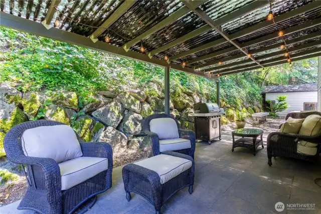 Immediately outside the kitchen french doors is this idyllic covered patio to enjoy sunny or rainy days, barbecue, etc. Beyond that are long benches waiting for a firepit or table (or combined?) Fiberglas patio awning will be hosed off before closing.