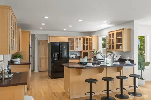 The updated kitchen is a true centerpiece of the home—designed for both daily living and entertaining. Featuring slab style stone countertops, chef inspired appliances, and abundant working counter space, it effortlessly blends function with style. Natural light floods the space through large windows that frame serene mountain views, creating a calm and inspiring atmosphere. Extensive Swedish-finish solid oak floors add warmth and continuity, extending into a cozy eating area and bar seating perfect for casual meals or conversation. A large pantry provides excellent storage, making this kitchen as practical as it is beautiful.