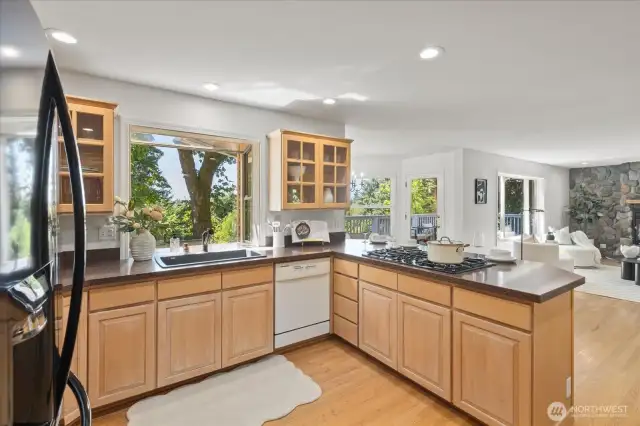 The kitchen features solid maple cabinets with rich wood grain and elegant glass-door upper accents, blending timeless craftsmanship with a touch of display-worthy sophistication.