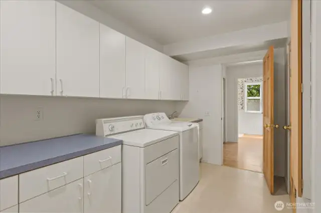 The spacious main floor laundry room offers plenty of room for laundry tasks and doubles as an ideal craft or hobby space. It includes a convenient laundry sink, a built-in ironing board, and a walk-in pantry for extra storage and organization.
