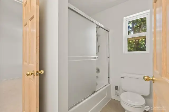 The second-floor bathroom includes a window that brings in natural light and fresh air, enhancing the bright and airy feel of the space.