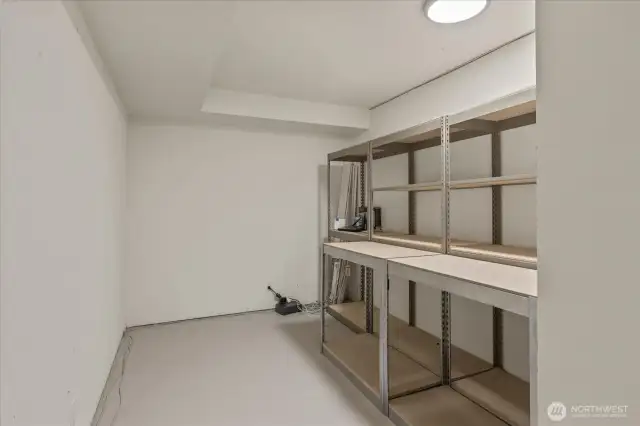 The lower level includes a storage area with built-in shelving—ideal for a wine room or extra storage—offering organized space to keep essentials neatly tucked away.