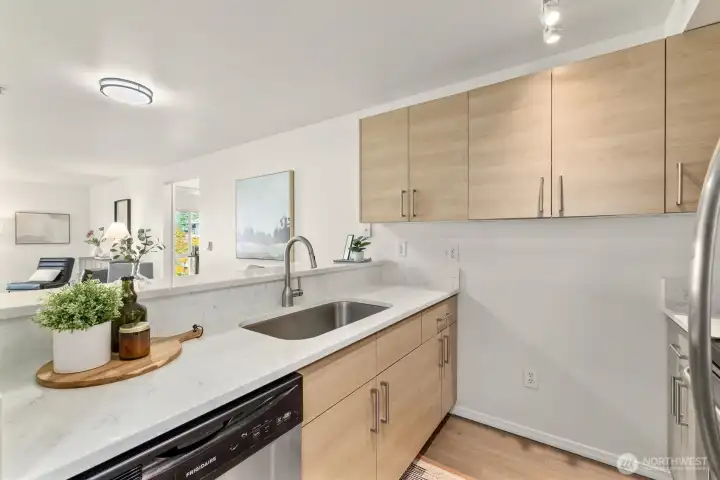 Open and bright kitchen features quartz countertops and stainless appliances.