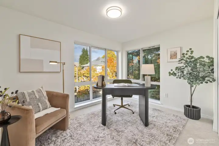 The second bedroom features 2 walls of windows with foliage-filled northeasterly views