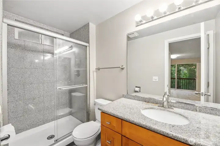Single vanity with granite counter and backsplash, and under mount sink  Shower with granite tile surround.  Tile floor