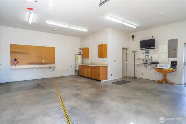 The shop has it's own water heater. The shop is wired with 220v. There is also an outdoor 220v plug outside. There are cabinets with a countertop abd sink. A 3/4 bath is through the door ahead.