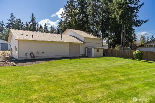 Looking from the back yard toward the shop. Back yard is partially fenced. The garage door makes it possible to drive through and drive around the shop. There is a small storage shed behind the shop.