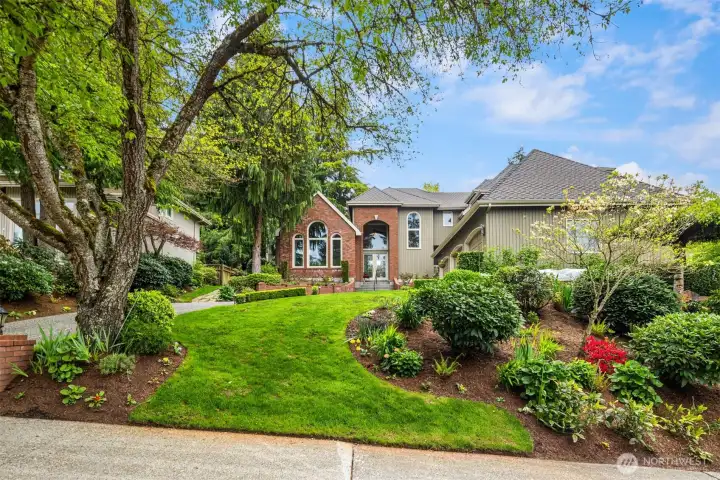 spacious, well-kept suburban home set back behind a lush, landscaped front yard