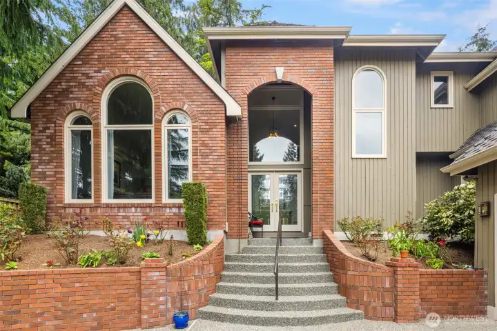 house features a mix of red brick and light-colored siding, with a steep, multi-gabled roof and large arched windows that give it an elegant, slightly traditional look