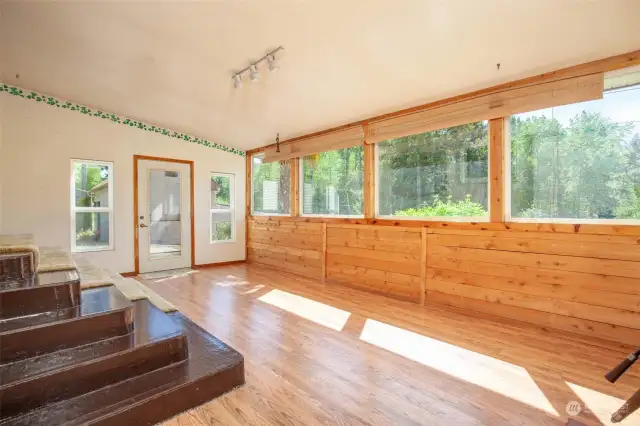 Huge windows in the sunroom capture the beautiful view of the woods