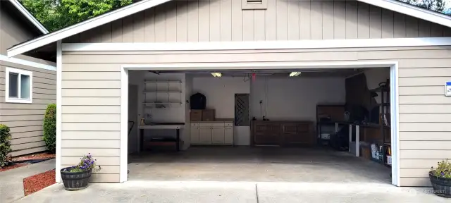 Large two car garage with work benches and shelving.