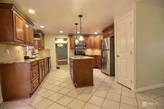 The elegantly designed traditional kitchen showcases cherry-stained raised panel cabinetry with top molding that enhances its classic charm. The bullnose granite countertops add a smooth, polished finish that complements the warmth of the cabinetry.