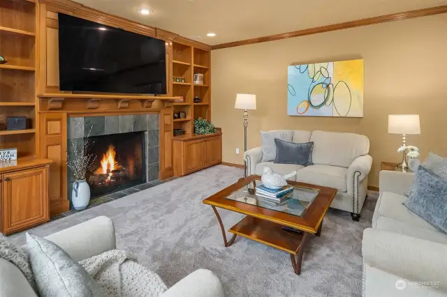 The adjoining family room with fireplace and a wall of built-in shelving.  The surround sound speaker system is provided here, in the kitchen, office, primary bedroom and bonus room.