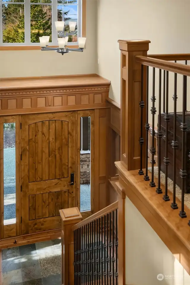 A stunning vaulted entry foyer, and main staircase to the upper-floor with wrought iron balusters.