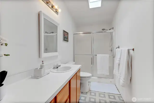 This is the light and bright primary bath with a skylight for plenty of natural light. Shower has nice bench seating. There is also a nice storage cabinet as you enter to the left not in this photo.