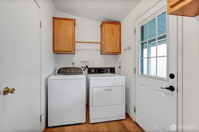 Utility room off the kitchen which includes the washer and dryer. The door to the left is a second entrance to the main hall bath and the door to the right leads outside to the covered walkway to the 2 car garage.