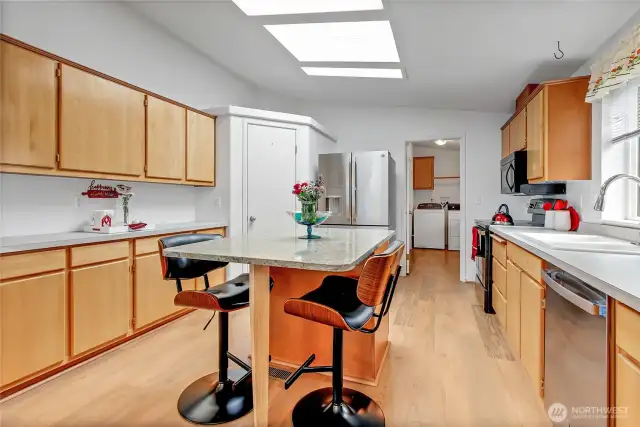 This is kitchen has so much counter space! Walk in pantry, large beautiful custom breakfast bar/island has a fabulous mix of colors. Virtually new appliances stay with the home. Skylights for a ton of light! At the far end leads to the utility room