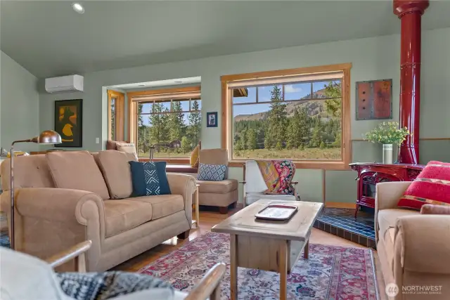 Brilliant living room graced by charming red wood stove adds ambiance and coziness in winter! And check out the   fabulous views from every window!
