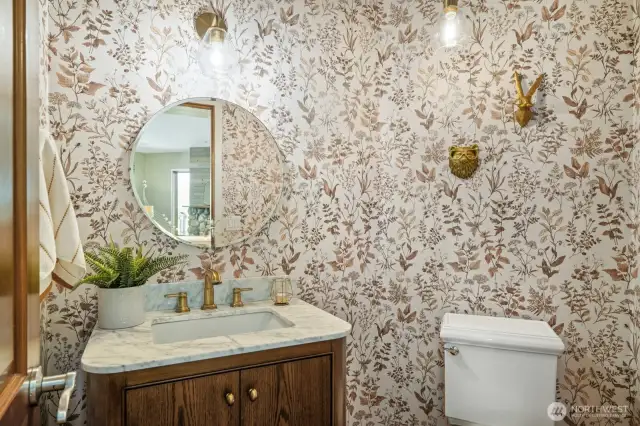 Impeccably tasteful half bath off the great room and garage, featuring a beautiful vanity and designer wallpaper.