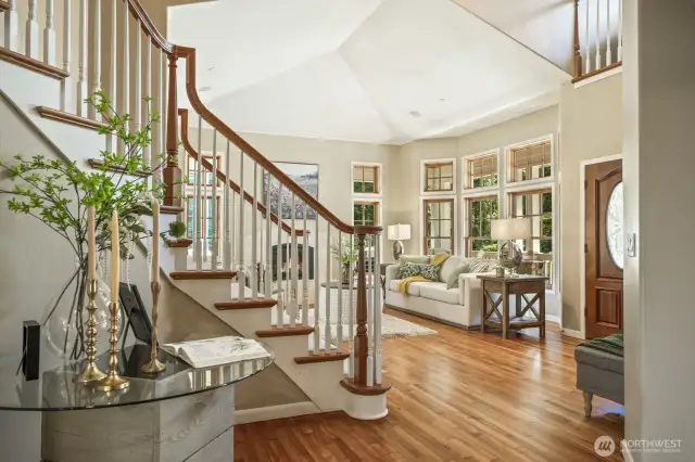 Vaulted ceilings soar through the living room and foyer, creating an open and airy atmosphere.