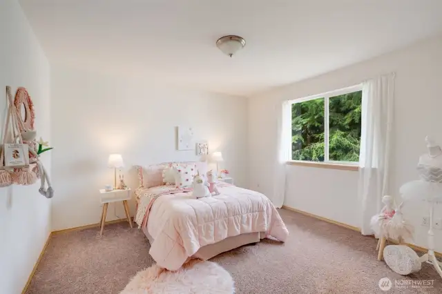 This darling third bedroom is also located upstairs, and overlooks picturesque greenery.