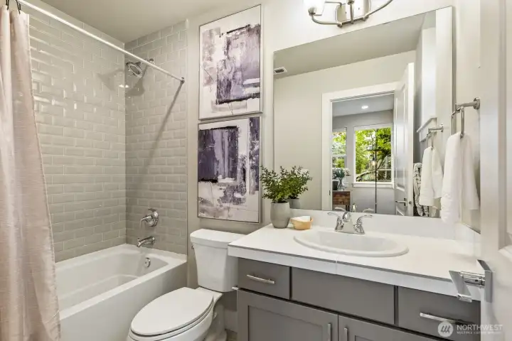 Main-floor ensuite bathroom w/ tub and shower and features upgraded tile including shower walls in tile all the way to the ceiling!